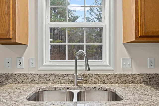 a kitchen with granite countertop a sink window and cabinets