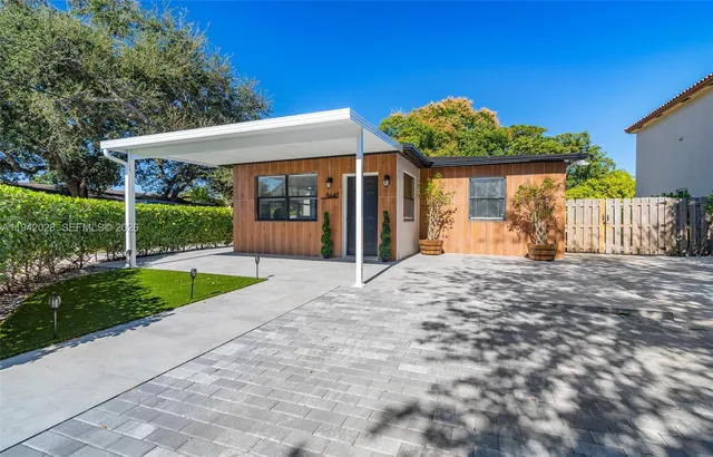 a view of a house with a small yard and a large tree