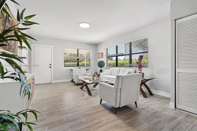 a living room with furniture floor to ceiling window and wooden floor