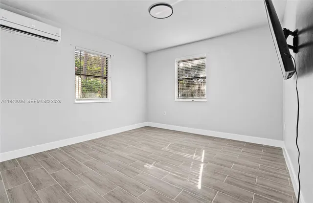 a view of an empty room with a window and wooden floor
