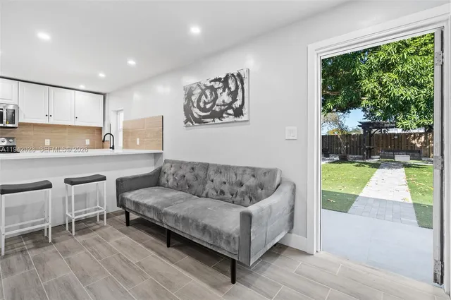 a living room with stainless steel appliances furniture and a wooden floor