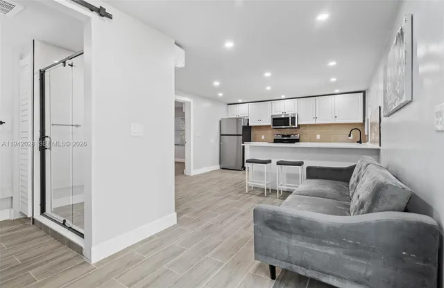 a living room with stainless steel appliances furniture and a kitchen view