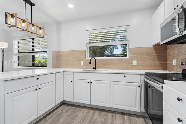 a kitchen with white cabinets and sink