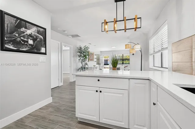 a kitchen with white cabinets and window