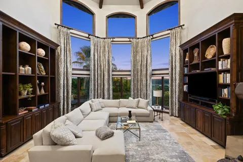 a living room with furniture a flat screen tv and floor to ceiling window