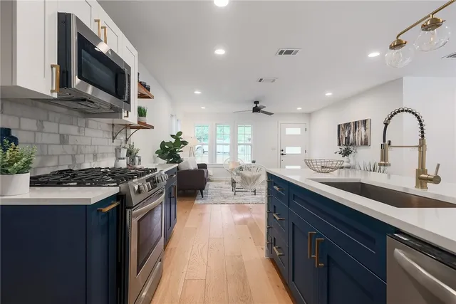 a kitchen with stainless steel appliances granite countertop a stove a sink dishwasher and a microwave oven with wooden floor