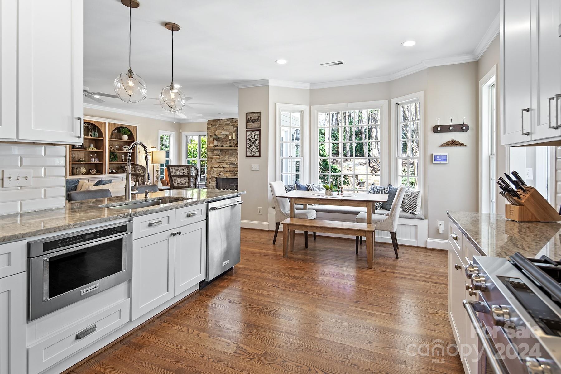 544 Ashby Drive Davidson, NC 28036 - Photo 10 of 40 a kitchen with stainless steel appliances granite countertop a stove a sink dishwasher and a fireplace with wooden floor