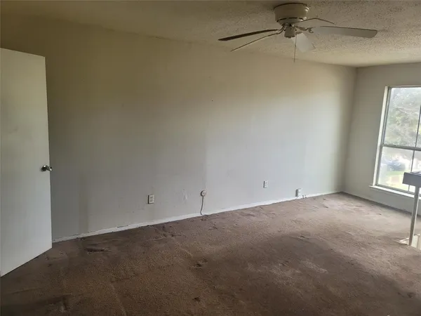 an empty room with a window and a fan