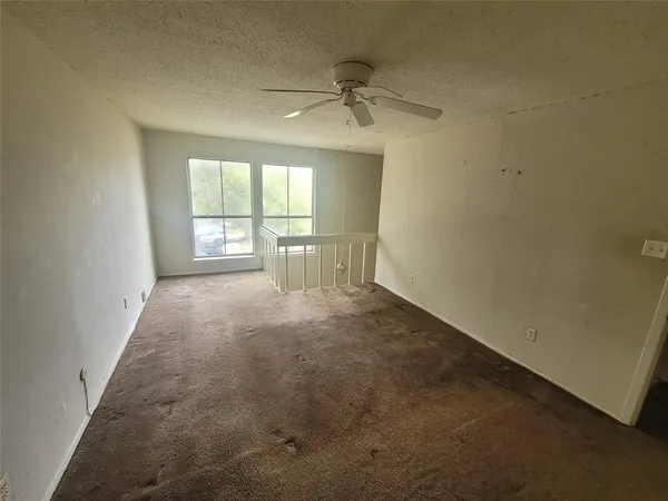 en empty room with windows and ceiling fan