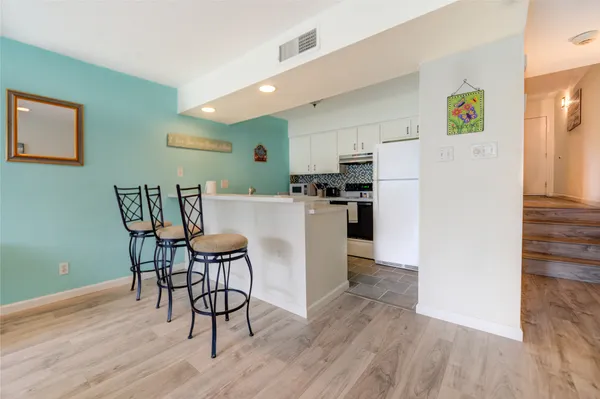 a kitchen with stainless steel appliances wooden floor and a refrigerator