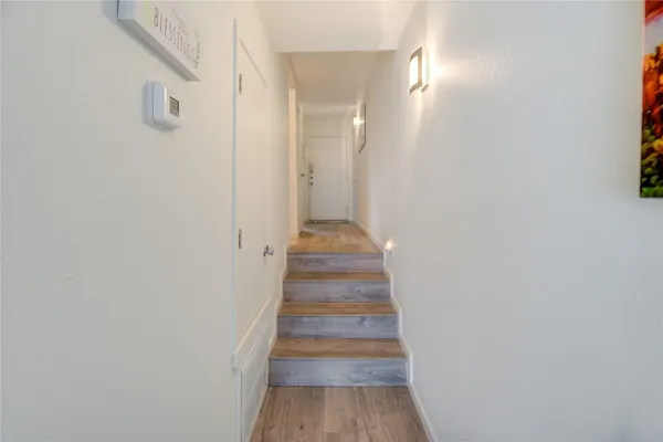 a view of a hallway with wooden floor and staircase