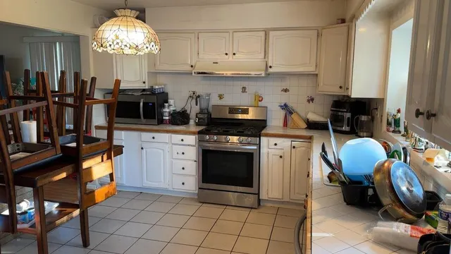 a kitchen with stainless steel appliances a stove a sink cabinets and a dining table