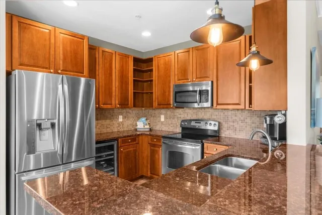 a kitchen with stainless steel appliances granite countertop a sink refrigerator and cabinets