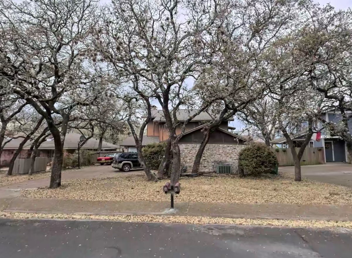 View of property featuring stone siding and driveway
