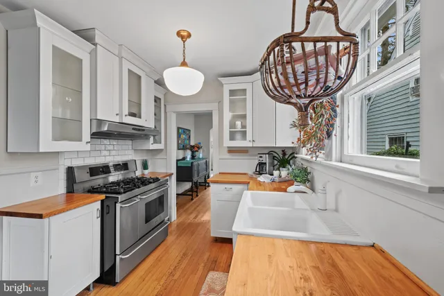 a kitchen with stainless steel appliances a stove a chandelier and wooden cabinets