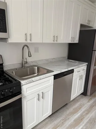 a kitchen with granite countertop white cabinets and black appliances