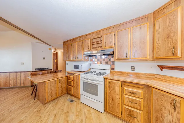 a kitchen with stainless steel appliances granite countertop a stove a sink dishwasher and a refrigerator with wooden floor