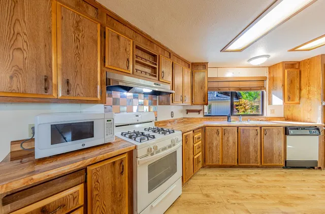 a kitchen with stainless steel appliances granite countertop a stove a sink and a microwave