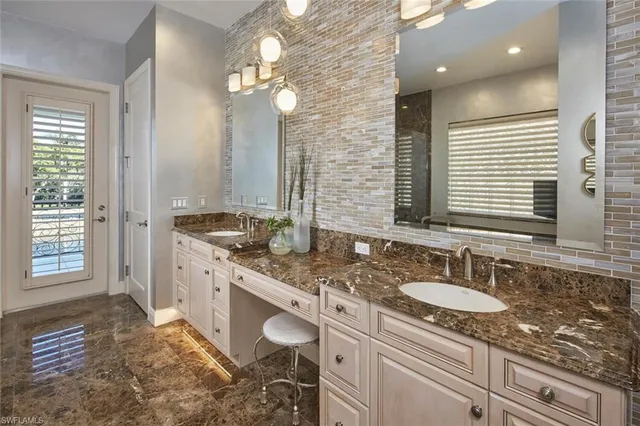 a bathroom with a granite countertop double vanity sink a mirror and a shower