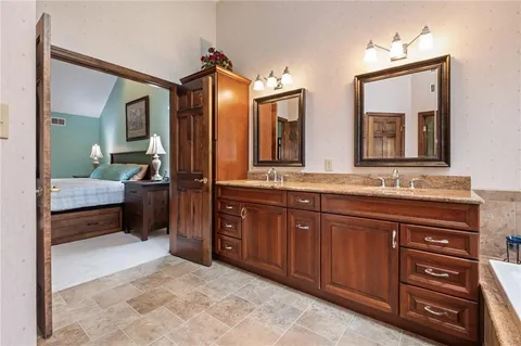 a bathroom with a granite countertop tub toilet a sink and a large mirror
