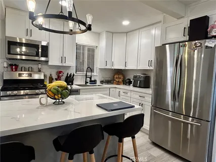 a kitchen with stainless steel appliances a sink a refrigerator and microwave