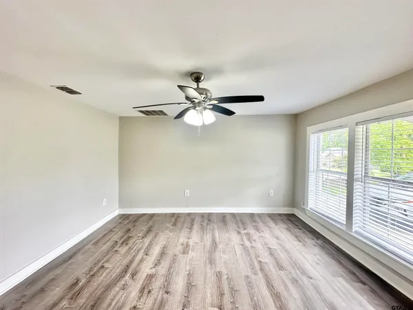 a view of an empty room with wooden floor and a window