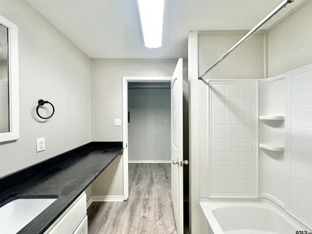 a bathroom with a granite countertop sink a mirror and a bathtub