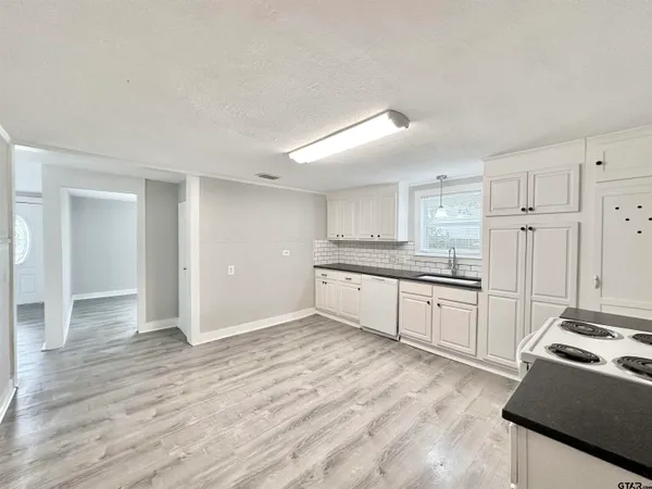 a large white kitchen with granite countertop a stove and a sink