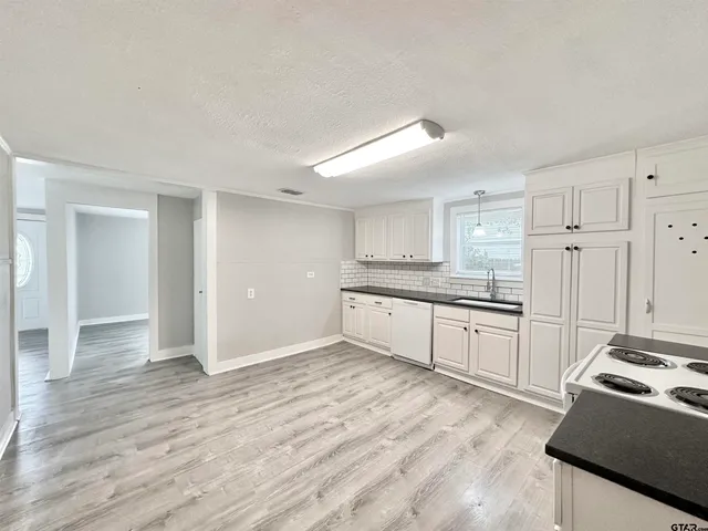 a large white kitchen with granite countertop a stove and a sink