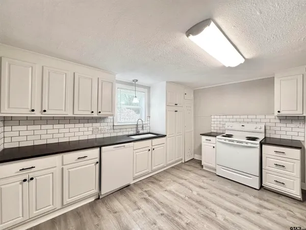 a kitchen with granite countertop white cabinets and white appliances