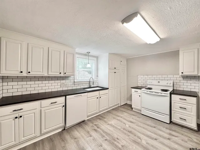 a kitchen with granite countertop white cabinets and white appliances