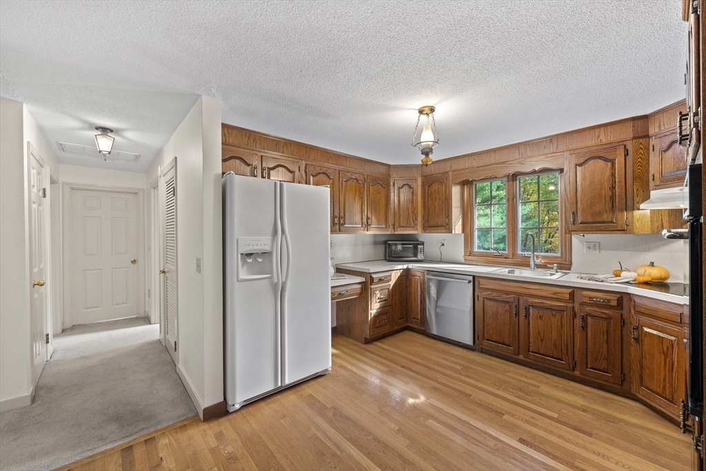 55 Warren Street Boylston, MA 01505 - Photo 9 of 30 a large kitchen with a refrigerator a sink dishwasher a stove and white cabinets with wooden floor