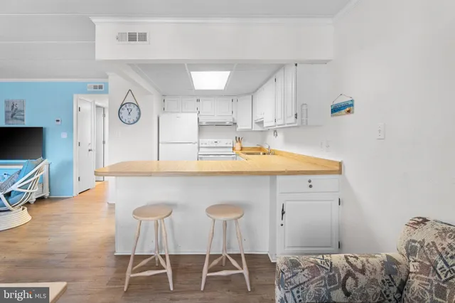 a kitchen with stainless steel appliances kitchen island a table chairs in it and white cabinets