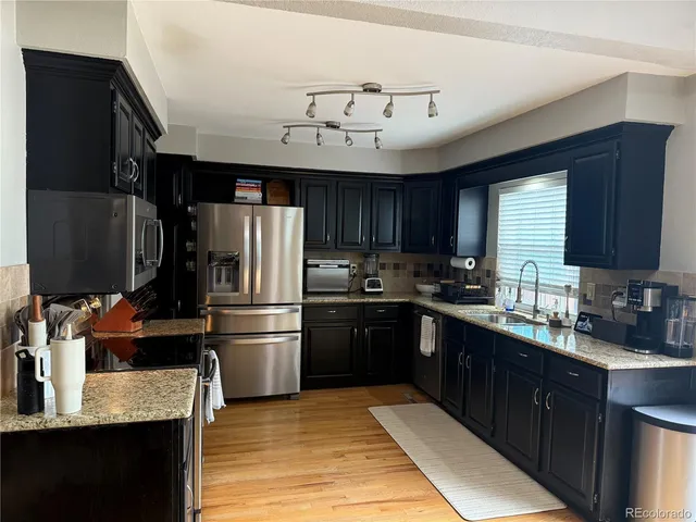 a kitchen with stainless steel appliances granite countertop a refrigerator a sink dishwasher a stove top oven a refrigerator and cabinets