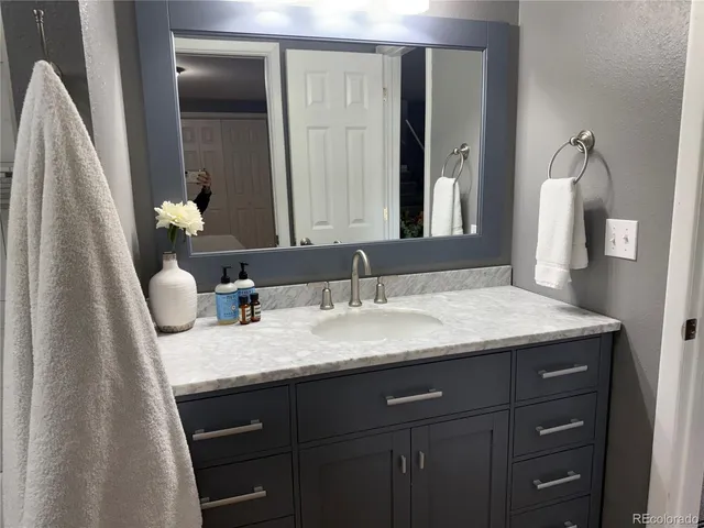 a bathroom with a granite countertop sink and a mirror