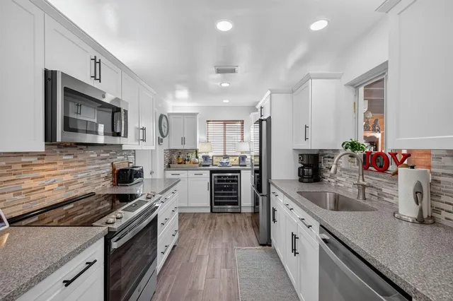 a large kitchen with a stove top oven a sink a microwave and wooden floor