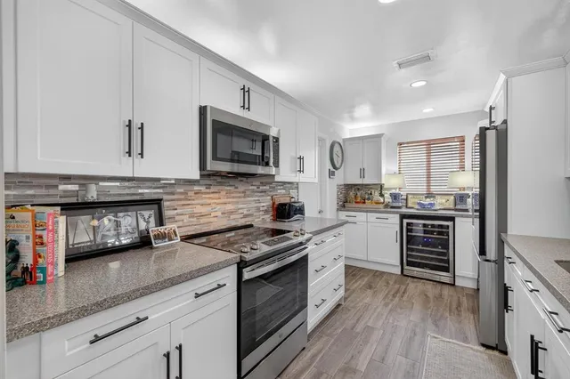 a kitchen with stainless steel appliances granite countertop a stove top oven a sink dishwasher and a refrigerator with wooden floor