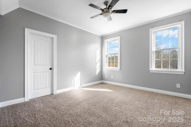 a view of a big room with windows and chandelier fan