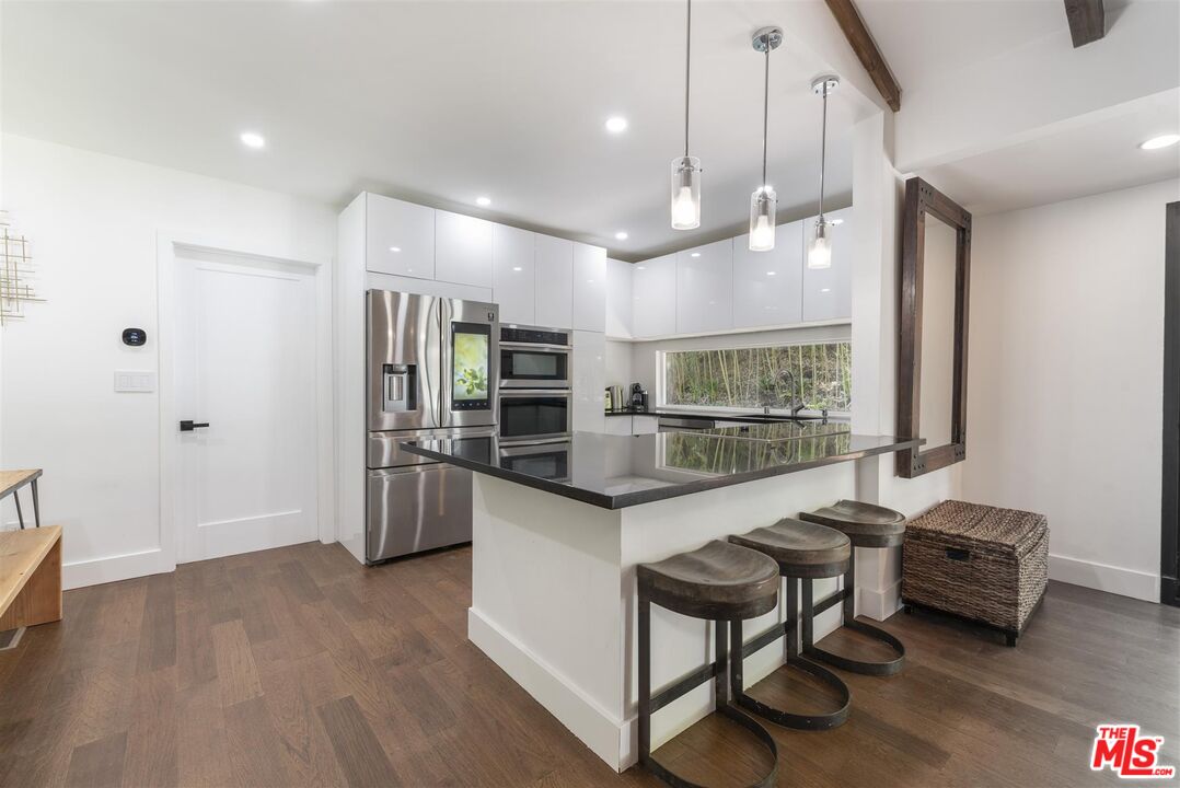 2429 Outpost Drive Los Angeles, CA 90068 - Photo 10 of 29 a kitchen with stainless steel appliances kitchen island granite countertop a refrigerator a stove a sink and a dining table with wooden floor