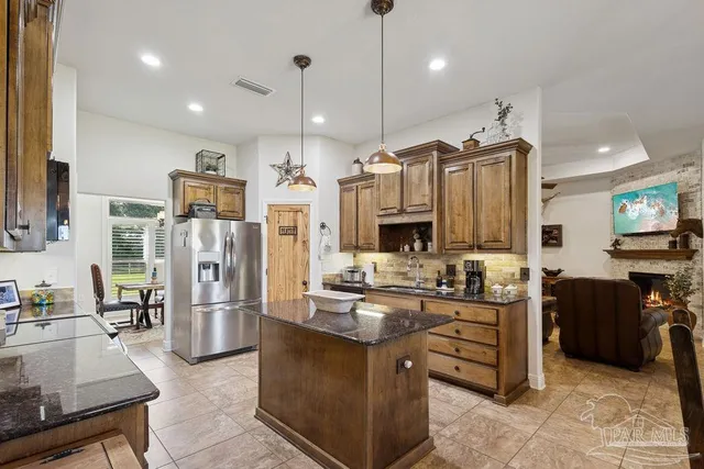 a large kitchen with stainless steel appliances kitchen island granite countertop a refrigerator and a stove top oven