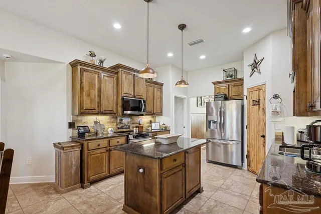 a kitchen with stainless steel appliances granite countertop a refrigerator a sink a stove and a refrigerator