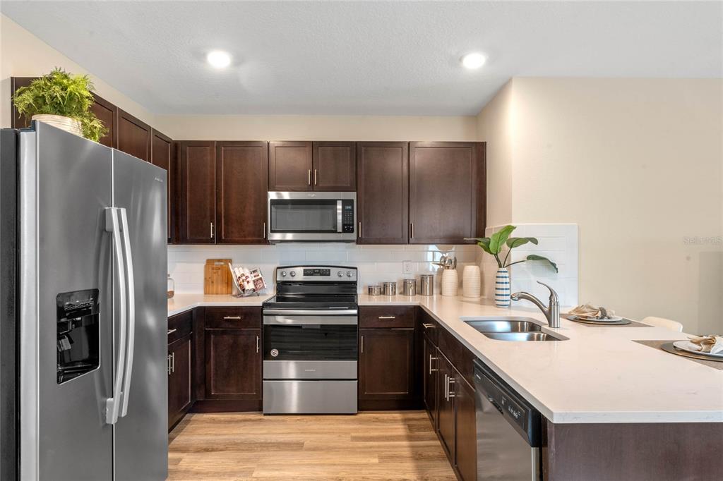 1008 Commons Way Port Port Orange, FL 32129 - Photo 7 of 27 a kitchen with stainless steel appliances a sink stove refrigerator and cabinets
