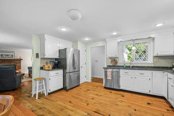 a kitchen with stainless steel appliances granite countertop a sink dishwasher a stove and a refrigerator with wooden floor