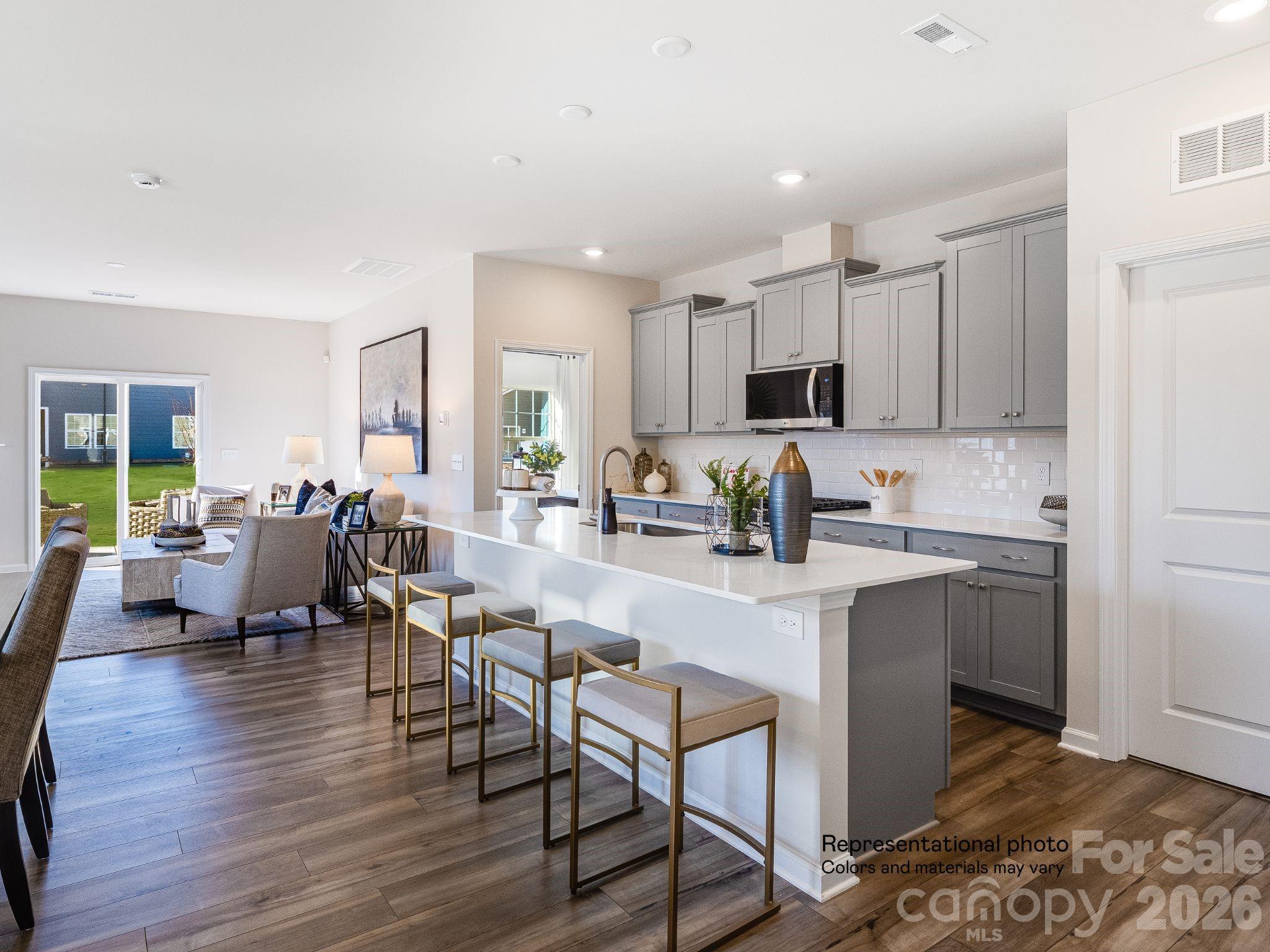 1015 Widgeon Way, Unit 203 Belmont, NC 28012 - Photo 4 of 17 a kitchen with stainless steel appliances granite countertop a stove top oven a sink dishwasher a dining table and chairs with wooden floor