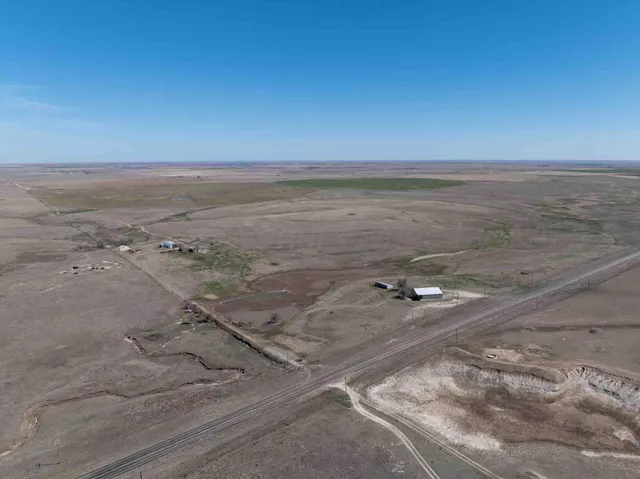 a view of a dry yard with wooden fence