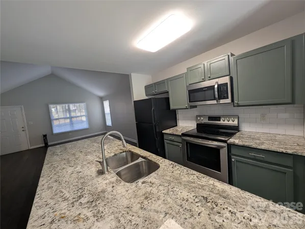 a kitchen with granite countertop a stove sink and microwave