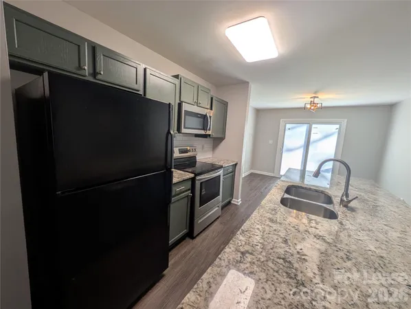 a kitchen with granite countertop stainless steel appliances a refrigerator stove top oven and sink