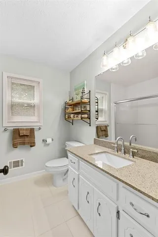 a bathroom with a granite countertop sink a toilet and a mirror