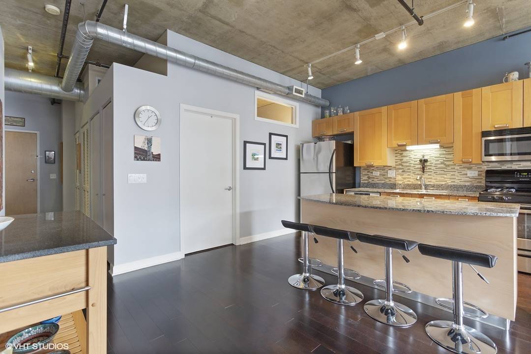 111 South Morgan Street, Unit 711 Chicago, IL 60607 - Photo 4 of 11 a room with stainless steel appliances kitchen island granite countertop a refrigerator a stove and a sink with wooden floor