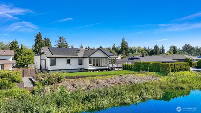 a view of a big house with a big yard plants and large trees